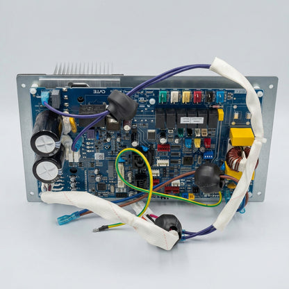 A large electronic control board or power supply unit with a blue circuit board, black capacitors, wiring, and a metal heatsink, photographed on a white sheet over a wooden surface.