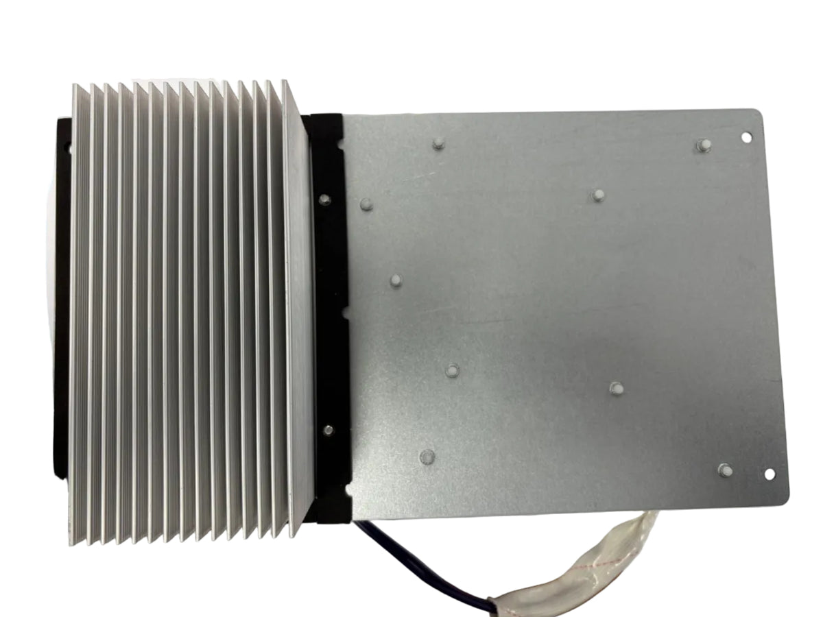A silver metal electronic heatsink and mounting plate assembly with attached wires, photographed from above on a white sheet over a wooden surface.